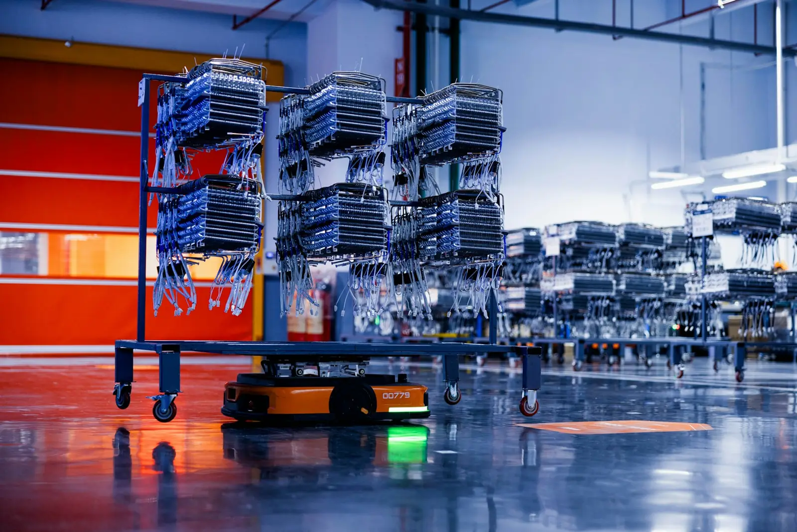 Autonomous mobile robots carrying shelving carts across a warehouse floor